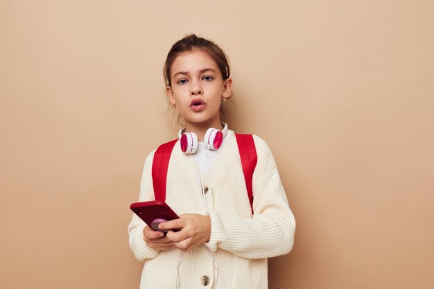 Bambina con telefono in posa zaino rosso infanzia inalterata