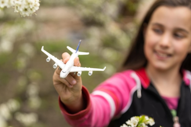 Bambina con un aeroplano giocattolo in giardino