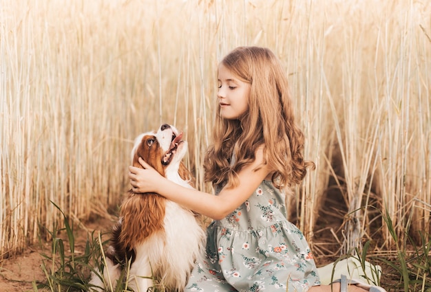 Bambina con un cane cavalier king charles spaniel che gioca in estate nella natura