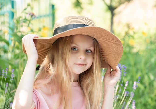 Bambina con un cappello di paglia circondata da fiori di lavanda