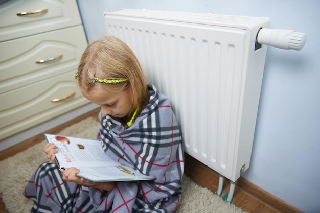 Bambina con un cappello seduto e crogiolarsi nella batteria. Libro da leggere.