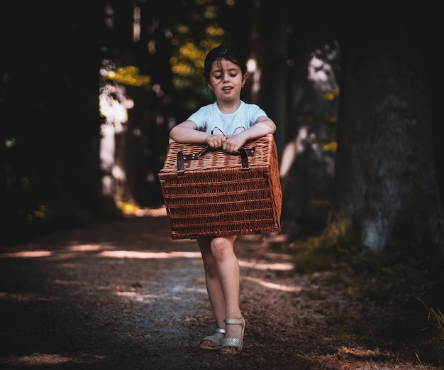 Bambina con un cesto di vimini nella foresta