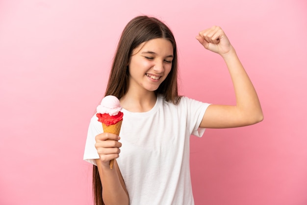 Bambina con un gelato alla cornetta su sfondo rosa isolato che celebra una vittoria