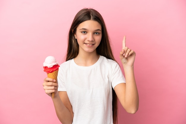 Bambina con un gelato alla cornetta su sfondo rosa isolato che indica una grande idea