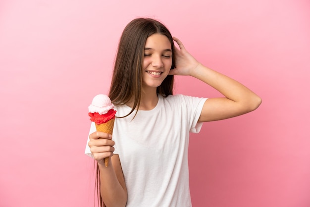 Bambina con un gelato alla cornetta su sfondo rosa isolato che sorride molto