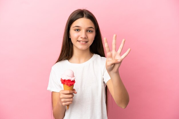 Bambina con un gelato alla cornetta su sfondo rosa isolato felice e contando quattro con le dita
