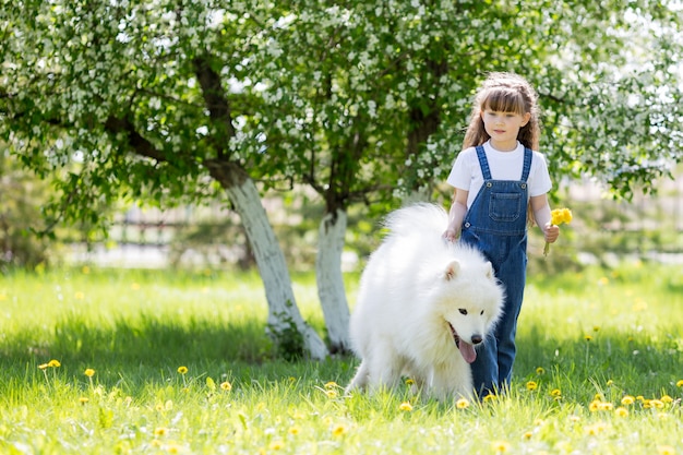 Bambina con un grande cane bianco nel parco.