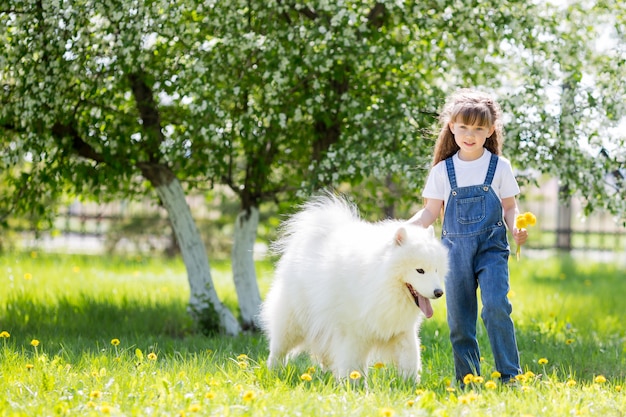 Bambina con un grande cane bianco nel parco.