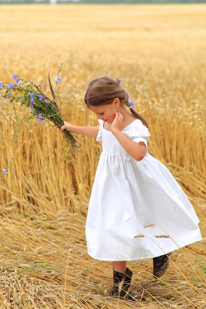 Bambina con un mazzo di fiori di campo sul campo