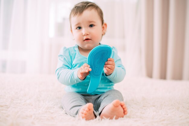 Bambina con un pettine blu in una giacca blu sul letto