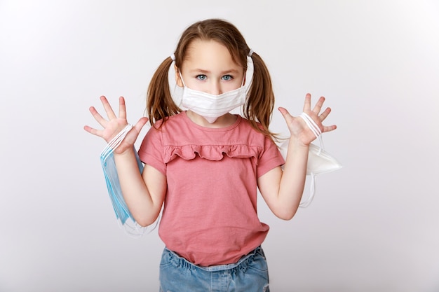Bambina con una mascherina medica sul viso che tiene molte maschere mediche e FFP2