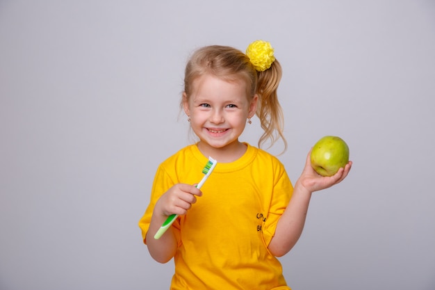 Bambina con uno spazzolino da denti, Bambina con uno spazzolino da denti e una mela.