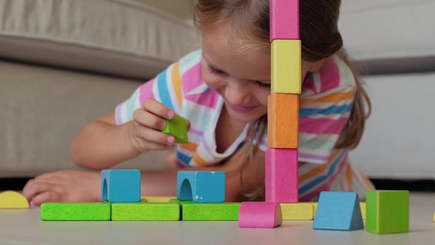 bambina concentrata a casa che gioca con blocchi di legno colorati.