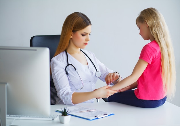 Bambina d'esame del medico bello con lo stetoscopio