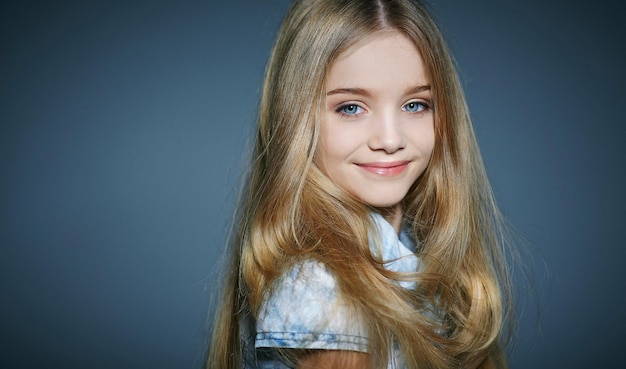 Bambina dai capelli lunghi sveglia che posa nello studio. Isolato su verde