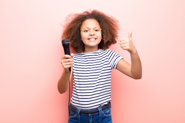 Bambina dell'afroamericano contro la parete piana con un microfono