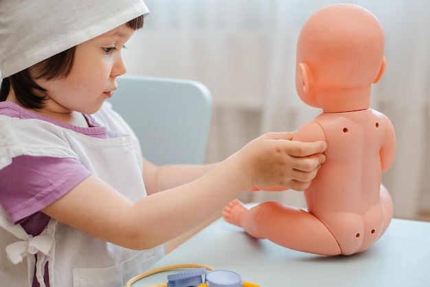 Bambina di 3 anni in età prescolare che gioca al dottore con la bambola Il bambino fa un giocattolo per iniezione