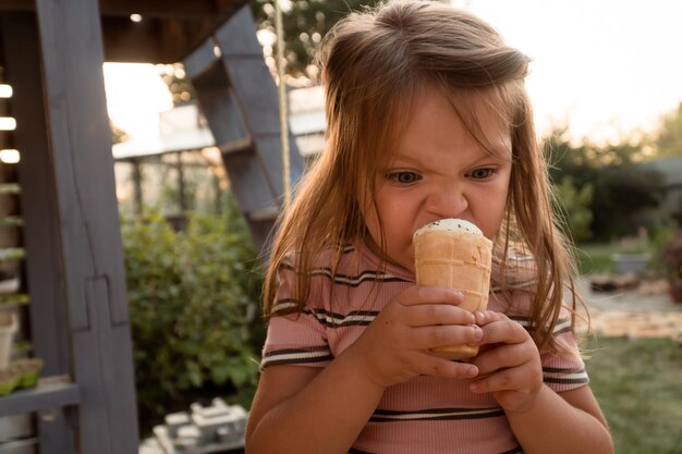 Bambina di tre anni che tiene il gelato in mano nel cortile di casa in estate