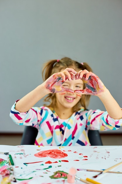 Bambina, disegna a casa e fai il cuore con le mani