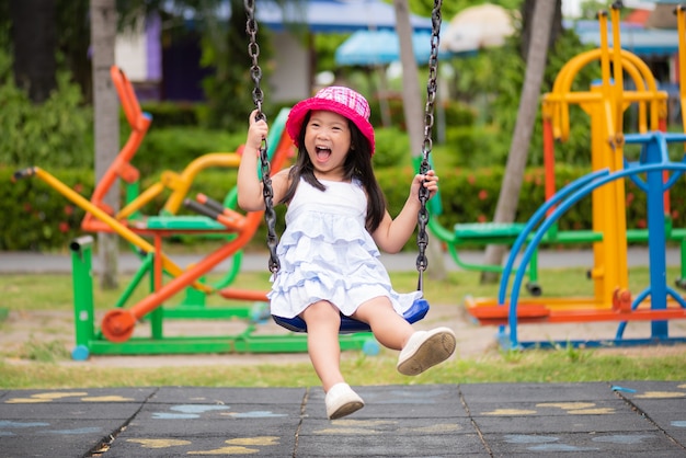 Bambina divertendosi con l&#39;oscillazione nel parco Campo da giuoco dei bambini.