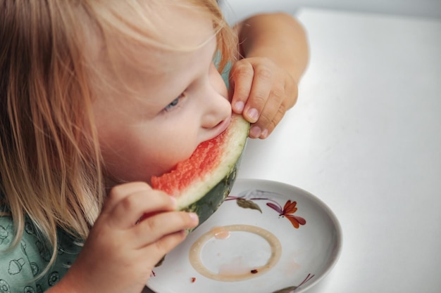Bambina divertente che mangia il primo piano dell'anguria