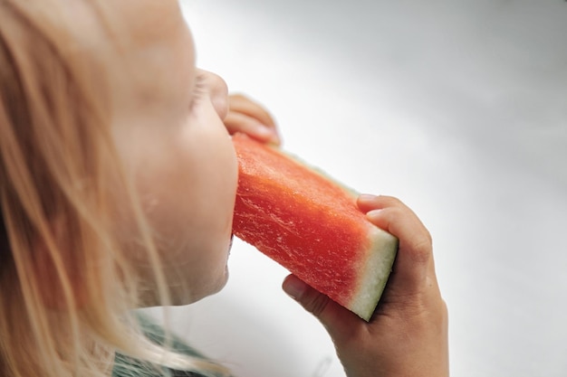 Bambina divertente che mangia primo piano dell'anguria Bambino carino con anguria all'interno Concetto di cibo sano estate Copia spazio