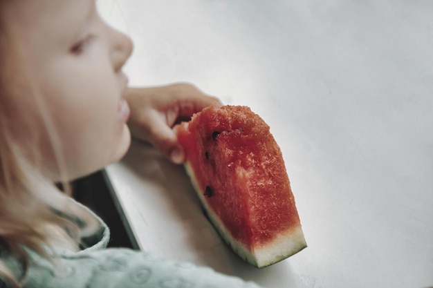 Bambina divertente che mangia primo piano dell'anguria Bambino carino con anguria all'interno Concetto di cibo sano estate Copia spazio