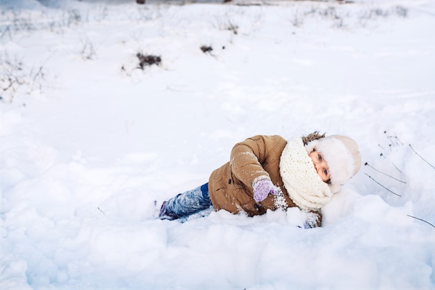 Bambina divertente che si trova in inverno nella neve