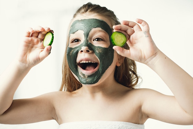 Bambina divertente con una maschera cosmetica fatta di argilla