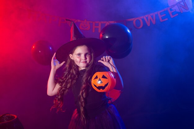 Bambina divertente in costume da strega per Halloween con zucca Jack.