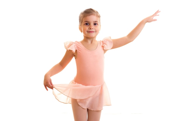 Bambina divertente in vestito rosa che balla su priorità bassa bianca in studio