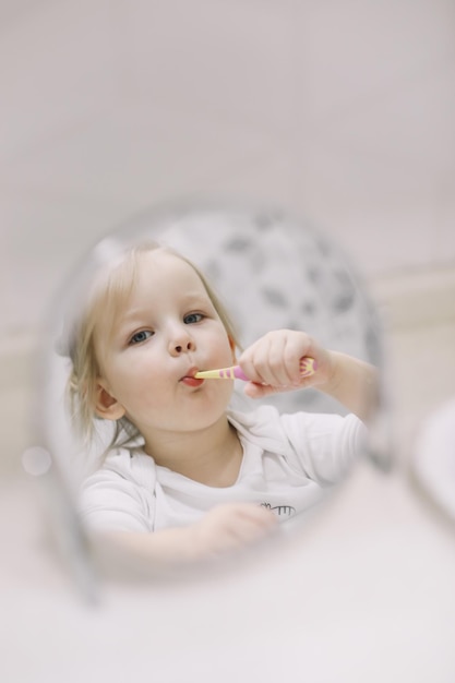 bambina divertente lavarsi i denti e lavarsi le mani nel riflesso del bagno nello specchio