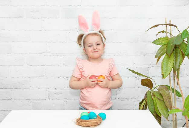 Bambina divertente una ragazza vestita da coniglio che tiene le uova di Pasqua nelle sue mani