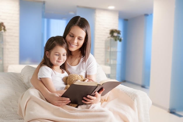 Bambina dolce con il libro di lettura della madre