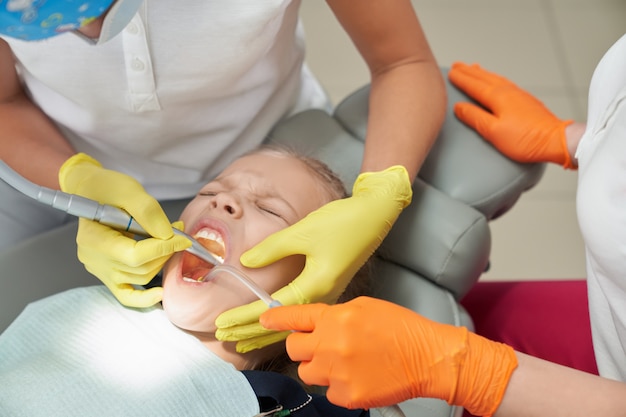 Bambina durante la procedura dolorosa in studio dentistico