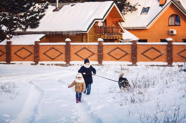 Bambina e ragazzo allegri stanno camminando con il loro cane nel parco in inverno