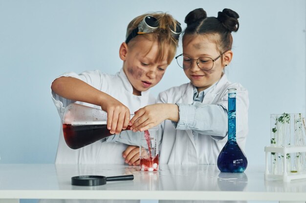 Bambina e ragazzo in camice bianco interpreta uno scienziato in laboratorio utilizzando attrezzature