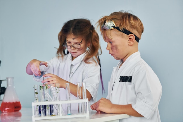 Bambina e ragazzo in camice bianco interpreta uno scienziato in laboratorio utilizzando attrezzature