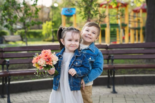 Bambina e ragazzo nel parco con un mazzo di fiori