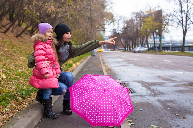Bambina e sua madre che camminano con l'ombrello in una giornata piovosa