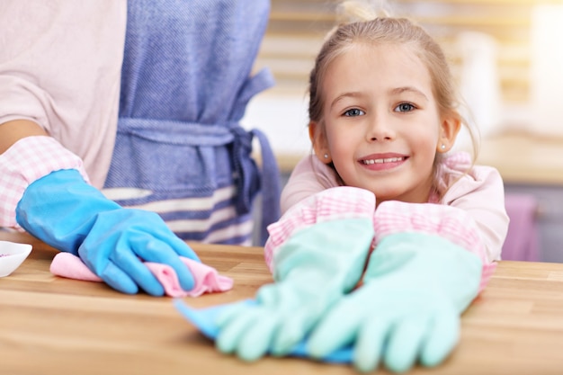 bambina e sua mamma in grembiule si divertono a pulire la cucina