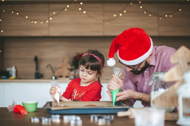 Bambina e suo padre che decorano i biscotti