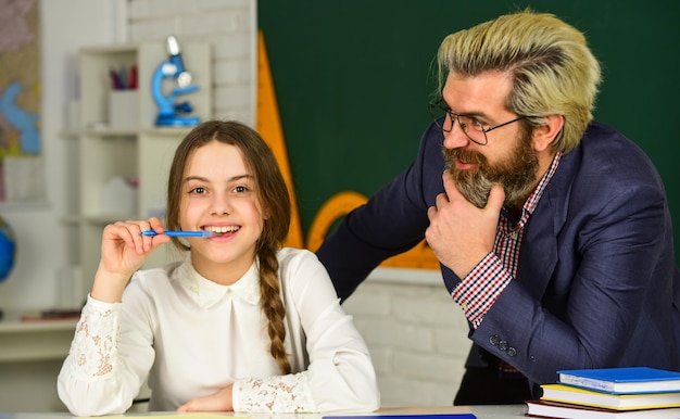 Bambina e uomo contro la lavagna Studente di consulenza Progetto homeschooling Giornata della conoscenza Bambino con insegnante in classe Scolara che studia con tutor personale Concetto di giorno degli insegnanti