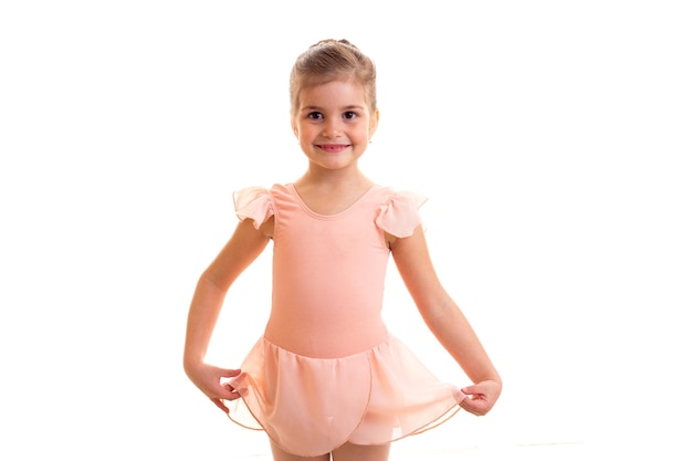 Bambina elegante in abito rosa che balla su sfondo bianco in studio