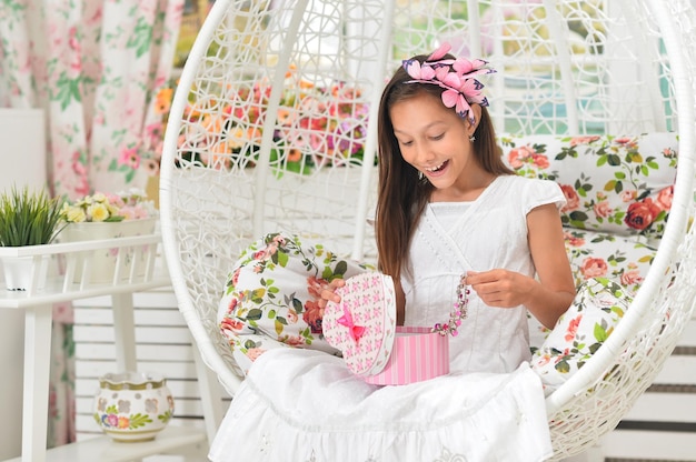 Bambina emotiva in vestito bianco che posa con il regalo