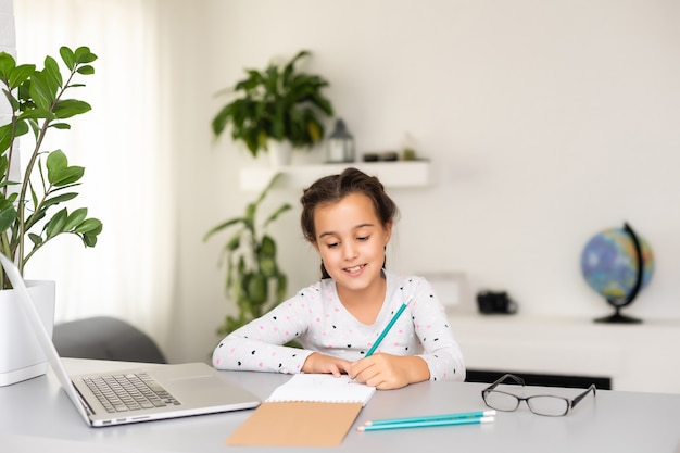 Bambina felice a casa che lavora con un laptop