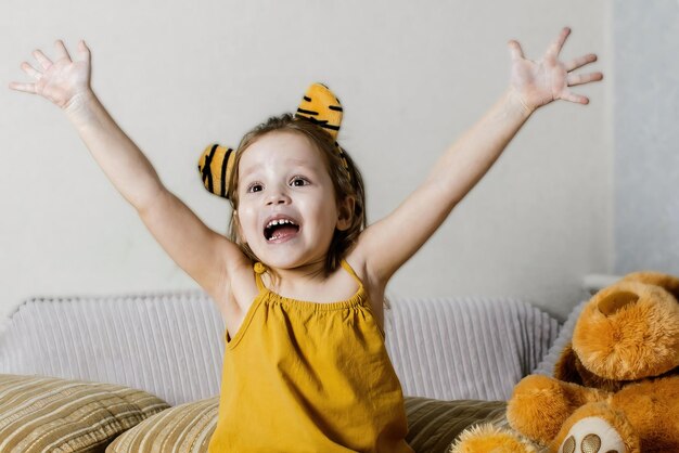 bambina felice a casa sul divano con i giocattoli