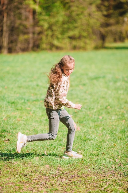 Bambina felice all'aperto nel parco in esecuzione e divertirsi