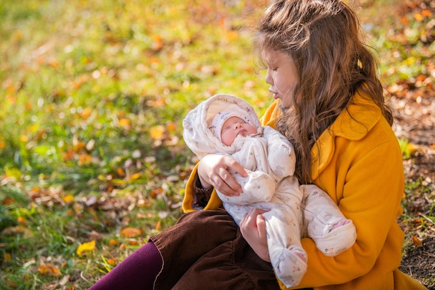 Bambina felice che abbraccia sua sorella appena nata nel parco autunnale in una giornata di sole