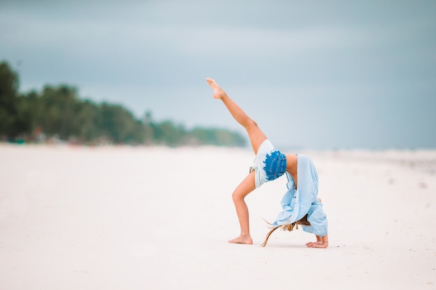 Bambina felice che cammina alla spiaggia durante la vacanza caraibica